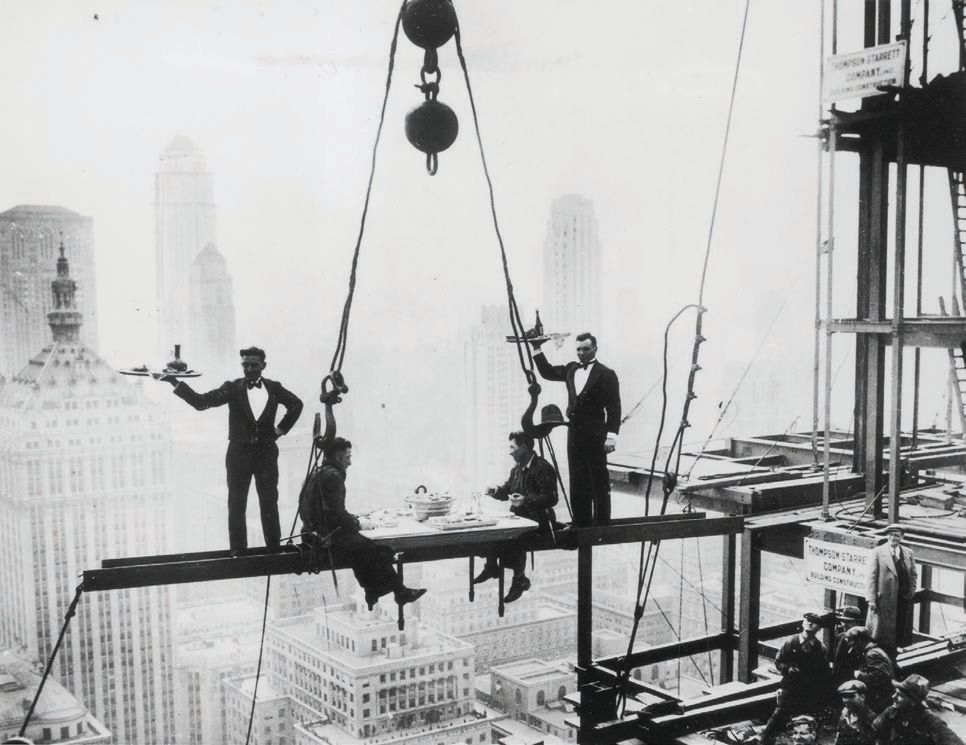 Two waiters in tuxedos serve Veuve Clicquot Champagne on a scaffolding overlooking New York City as featured in The Impossible Collection of Champagne (Assouline) TWO WAITERS PHOTO © PHOTO BY KEYSTONE/GETTY IMAGES; PHOTO COURTESY OF ASSOULINE