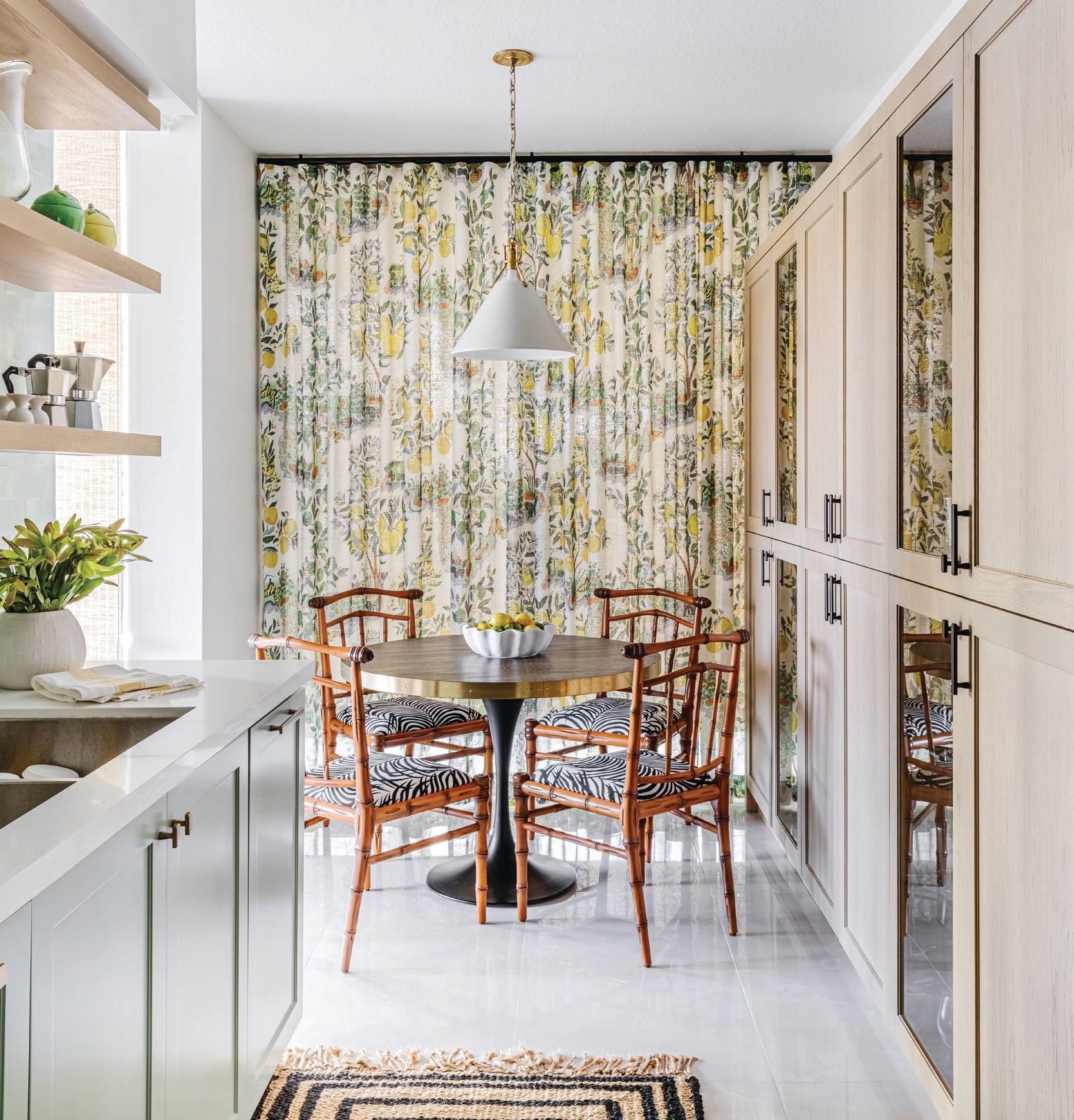 Dainty bamboo chairs fitted with Iconic zebra fabric juxtapose Citrus Garden linen draperies in the kitchen—both prints from Schumacher (schumacher.com). “The joyful color mix in these textiles perfectly complements the pastel cabinetry, hewn brass hardware and black powder-coated fixtures,” says designer Sabrina Albanese. PHOTO BY JEANNE CANTO