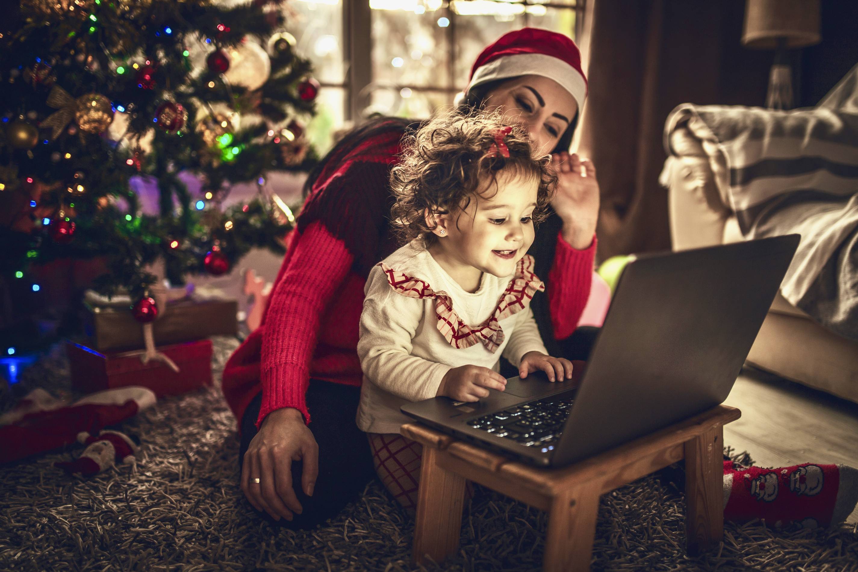 a kid and their mom play on a computer at christmas