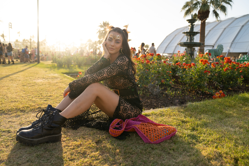 a woman sits on the grass at coachella