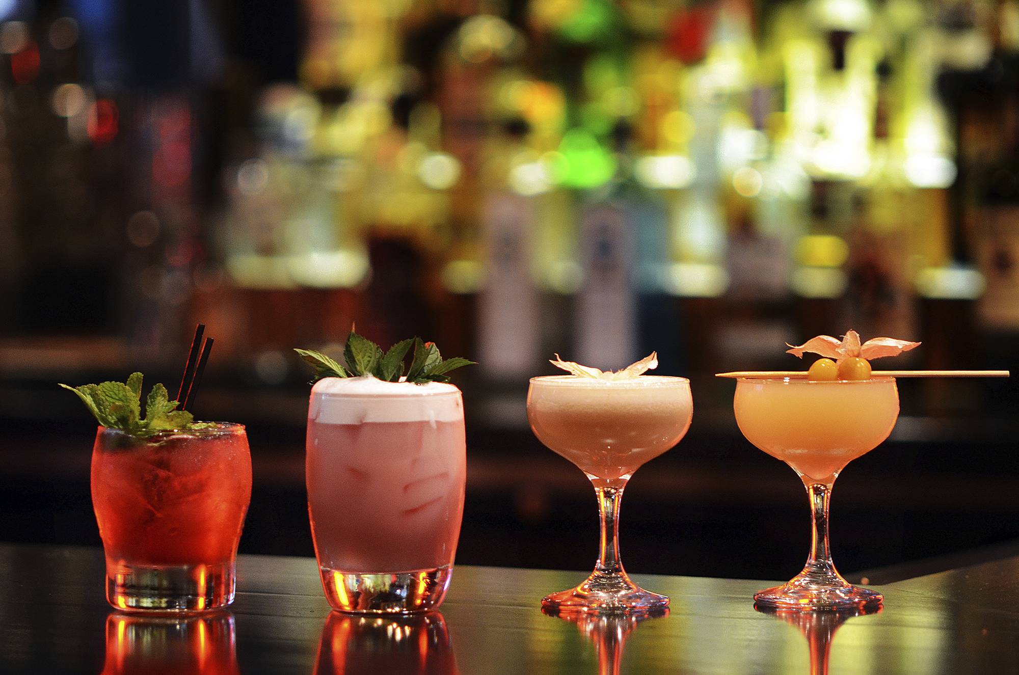 a lineup of craft cocktails on a bar