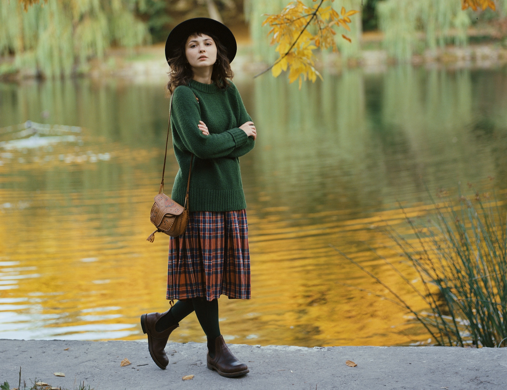 a woman walks by a lake in fall fashion