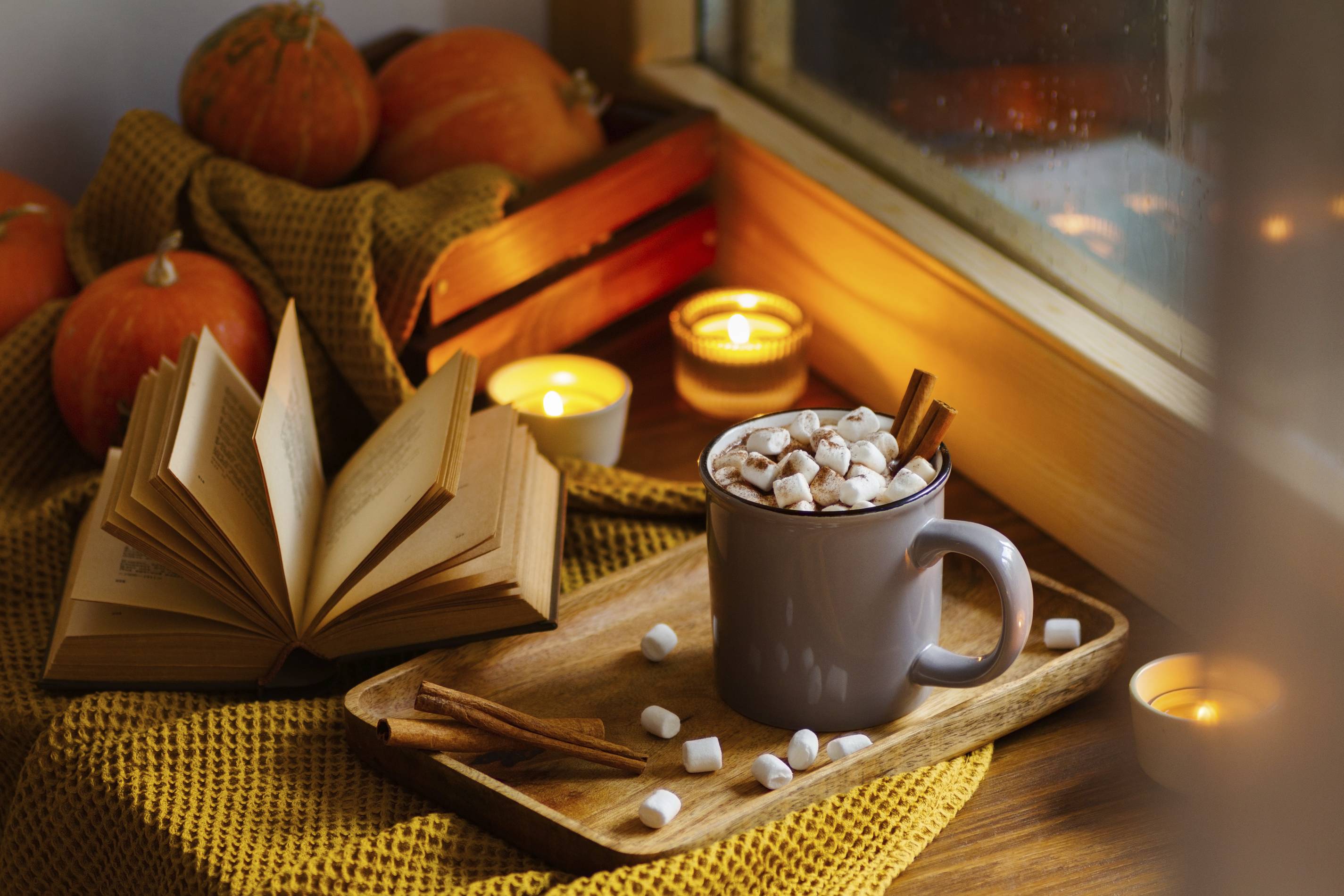 fall mood with coffee mug, book, pumpkins and candles