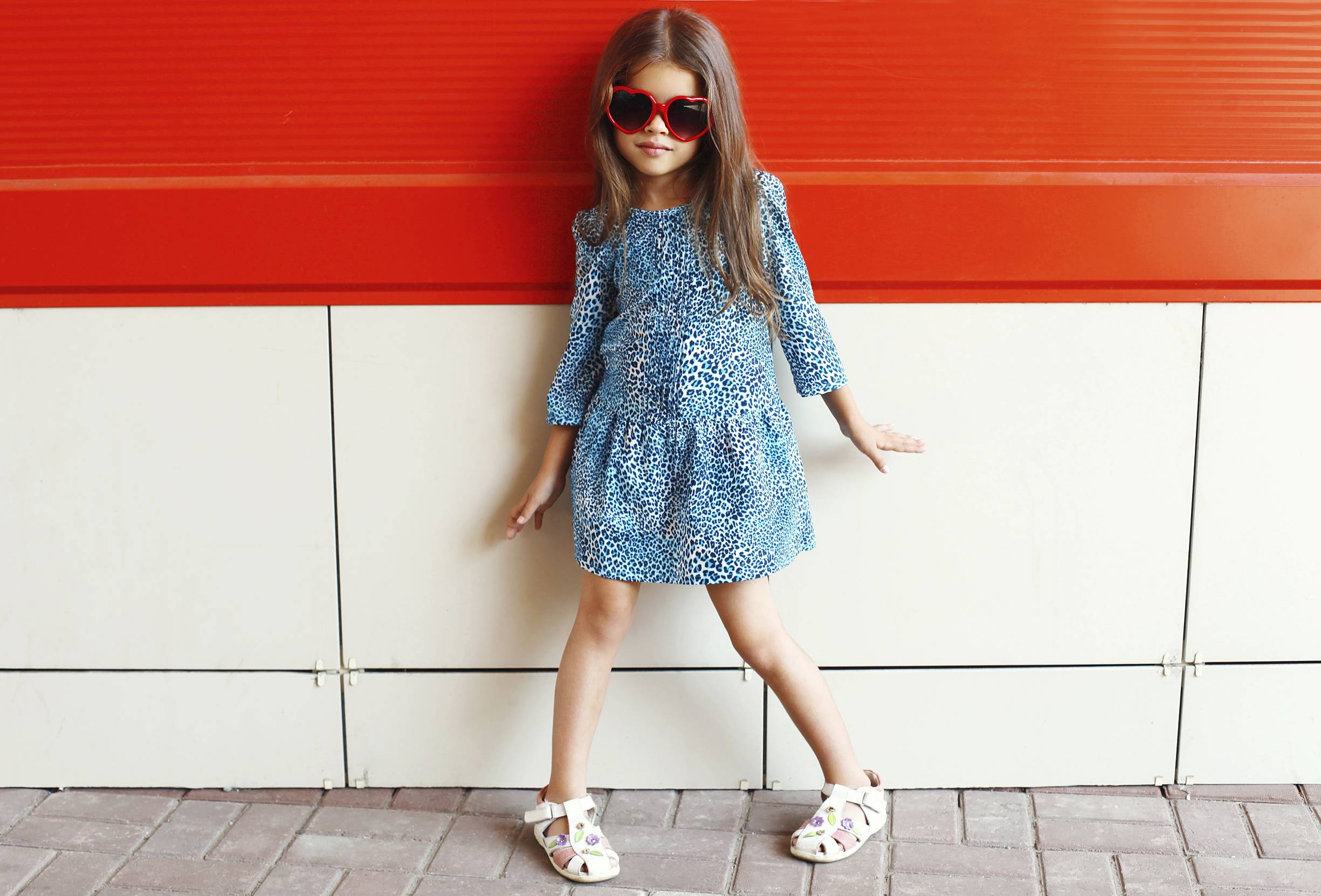 a little girl poses in a dress and cool sunglasses