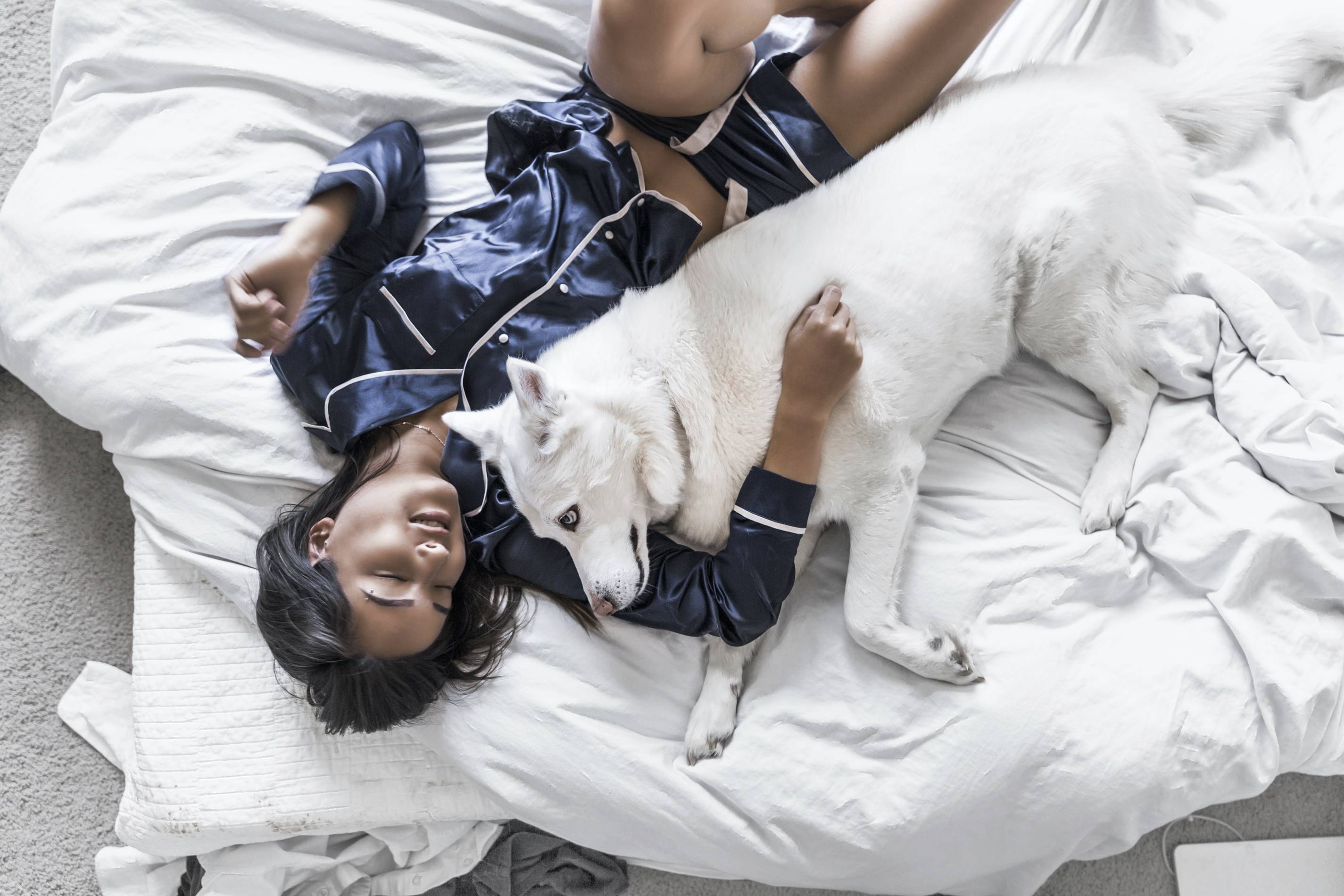 woman lounges in pajamas with her dog