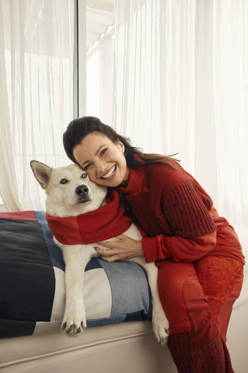 Fran Drescher in a sweatsuit hugging a dog in a pet bed from ThredUp holiday collection 2022